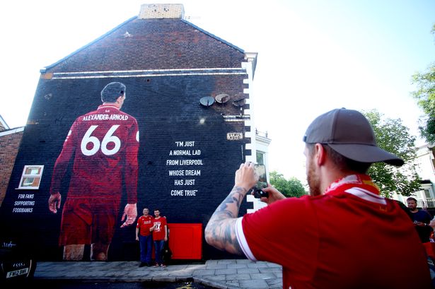 Liverpool fans take pictures in front of the new Trent Alexander-Arnold mural. 