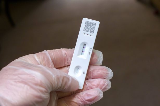 Adult hand with protective glove with the Test Result by Using self Rapid Test Device for COVID-19 Coronavirus. 