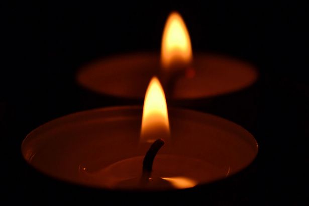 The flames of two tealights surrounded by darkness.