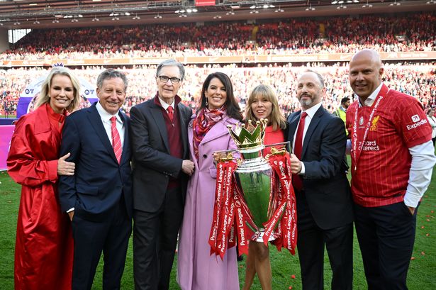 LIVERPOOL, ENGLAND - MAY 25: (L-R) Jennifer Ashton, Tom Werner, Chairman of Liverpool, and John Henry, Principle Owner of Liverpool, Linda Pizzuti Henry, Michael Gordon, President of Fenway Sports Group, and Arne Slot, Manager of Liverpool 2pose for a photograph with the Premier League trophy, as Liverpool are crowned the Champions of the Premier League for the 2024/25 Season, following the Premier League match between Liverpool FC and Crystal Palace FC at Anfield on May 25, 2025 in Liverpool, England. (Photo by Michael Regan/Getty Images/Getty Images For The Premier League)