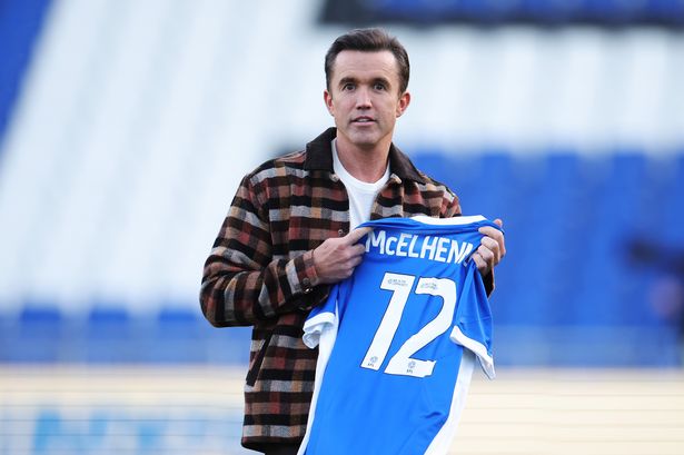 Wrexham co-owner Rob McElhenney holds up a Birmingham City shirt gifted to him by Tom Brady