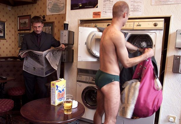 A customer at the Caledonia public house in Liverpool loads one of the pub's washing machines whilst having a pint Tuesday November 21 2000