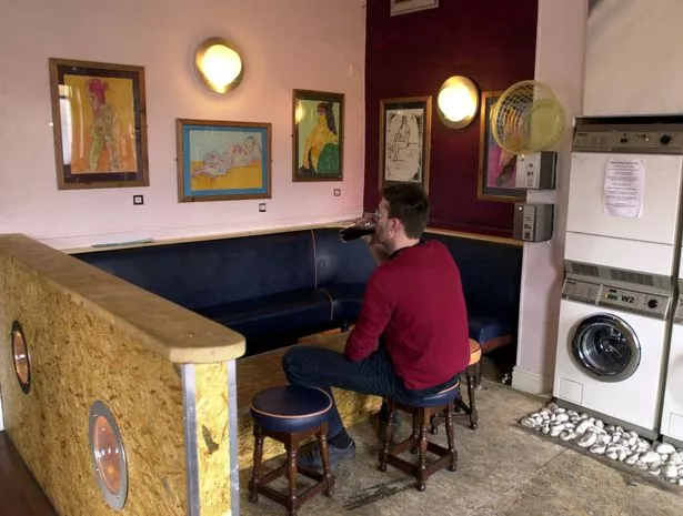 Art exhibition alongside washing machines at caledonia pub on catherine street Liverpool ingo akcher admires the artwork of sue lucine