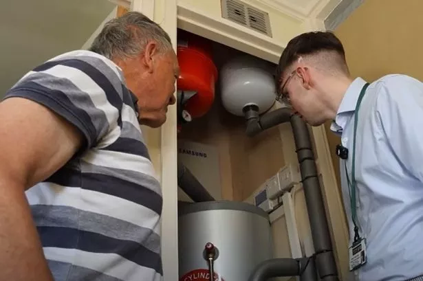 Kenneth Smith (Left) looking at heat pump cylinder in his Dudley home. PIC: WMCA