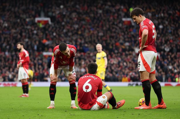 Lisandro Martinez speaks to teammate Diogo Dalot as he sits on the pitch after picking up an injury during the Premier League match between Manchester United FC and Crystal Palace FC at Old Trafford. 