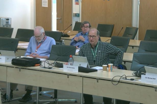 Men in shirts sat at desk at council meeting