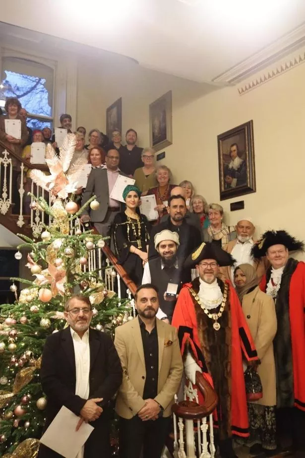 Two men in lord mayor's robes with recipients of medals stood on a large curved staircase