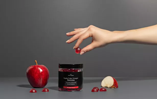 A hand holding one of the gummies above the pot 