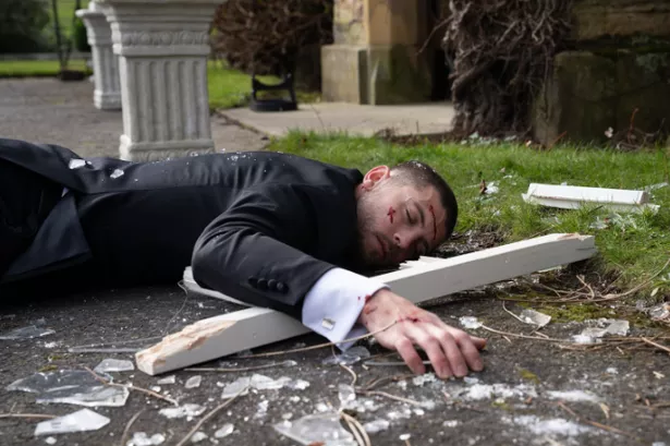 Emmerdale's Joe Tate lying face down on the ground with blood and shattered glass around him