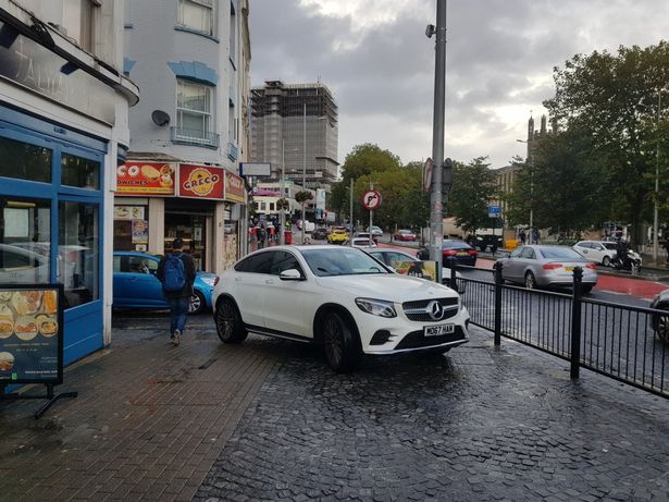 An SUV parked on a busy pavement in the city centre