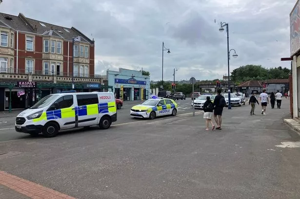 Police van and cars parked at Barry Island