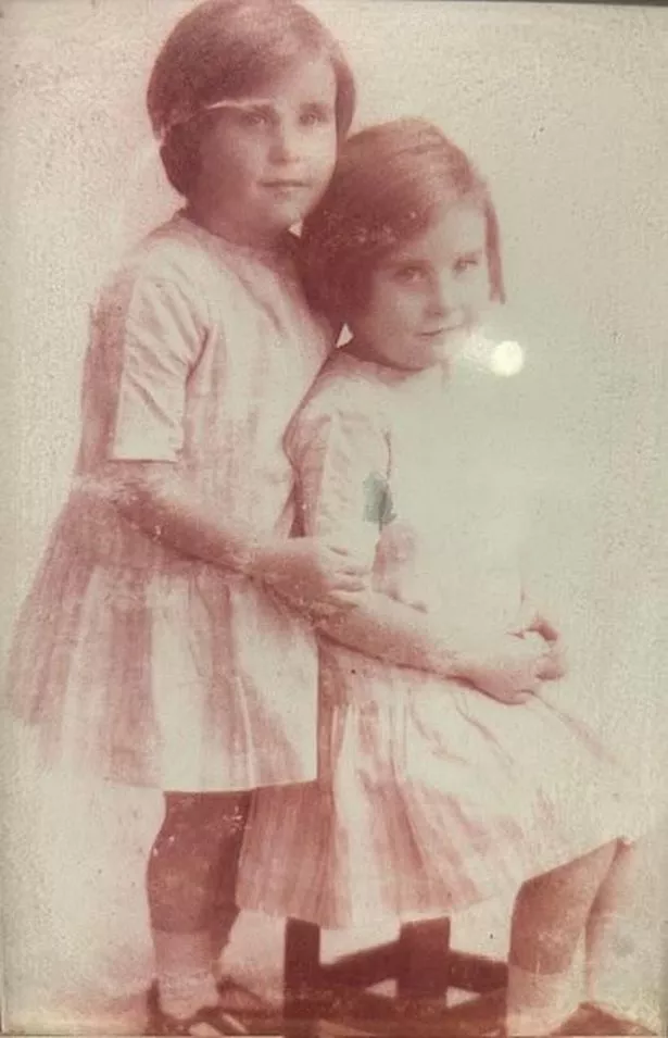 An old photograph of two children with bobs wearing a dress