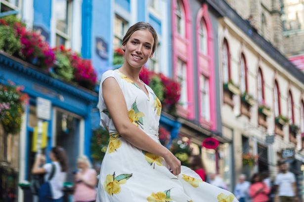 young woman in dress, exploring architectural beauty of Victoria street in Edinburgh on a sunny summer day