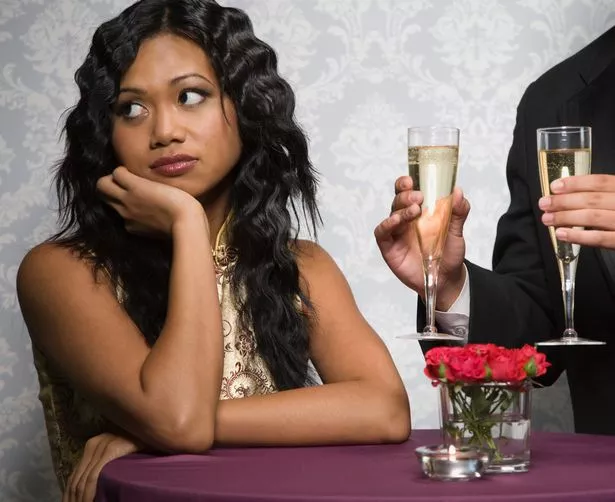 A woman looks away rudely while being offered a glass of champagne