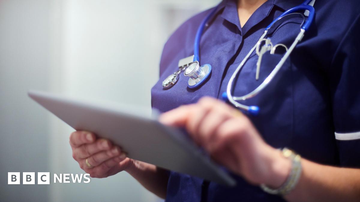 A close up image of a medical professional typing on a tablet with a stethoscope around her neck. You cannot see her face.