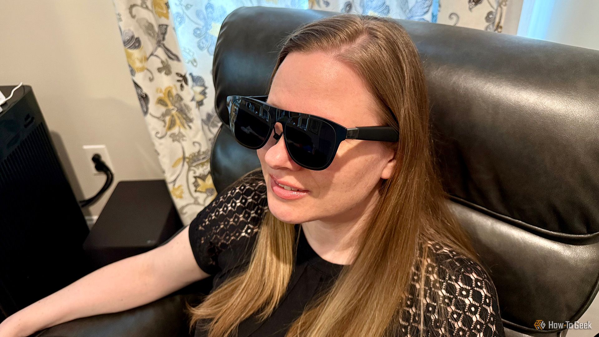 XREAL One AR Glasses being worn by a seated woman.