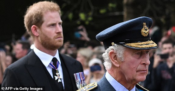 TOPSHOT - Britain's King Charles III and Britain's Prince Harry, Duke of Sussex walk behind the coffin of Queen Elizabeth II, adorned with a Royal Standard and the Imperial State Crown and pulled by a Gun Carriage of The King's Troop Royal Horse Artillery, during a procession from Buckingham Palace to the Palace of Westminster, in London on September 14, 2022. - Queen Elizabeth II will lie in state in Westminster Hall inside the Palace of Westminster, from Wednesday until a few hours before her funeral on Monday, with huge queues expected to file past her coffin to pay their respects. (Photo by LOIC VENANCE / AFP) (Photo by LOIC VENANCE/AFP via Getty Images)