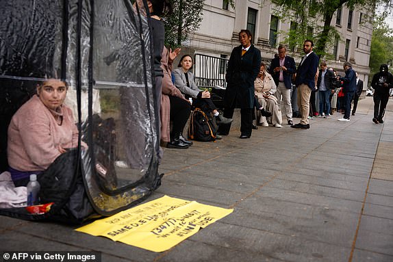 A woman sits on a shelter as people wait in line outside the Southern District of New York Federal Court, as jury selection begins in Sean "Diddy" Combs' federal sex crimes trial in New York on May 5, 2025. Jury selection begins Monday in New York in the blockbuster federal sex trafficking trial of music mogul Sean "Diddy" Combs, who stands accused of years of harrowing abuse. (Photo by kena betancur / AFP) (Photo by KENA BETANCUR/AFP via Getty Images)