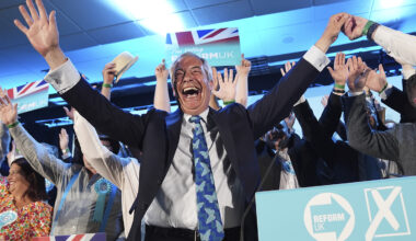 Nigel Farage with his arms raised in the air in celebration.