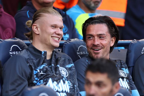 Haaland and Grealish laughing on the Man City subs bench.