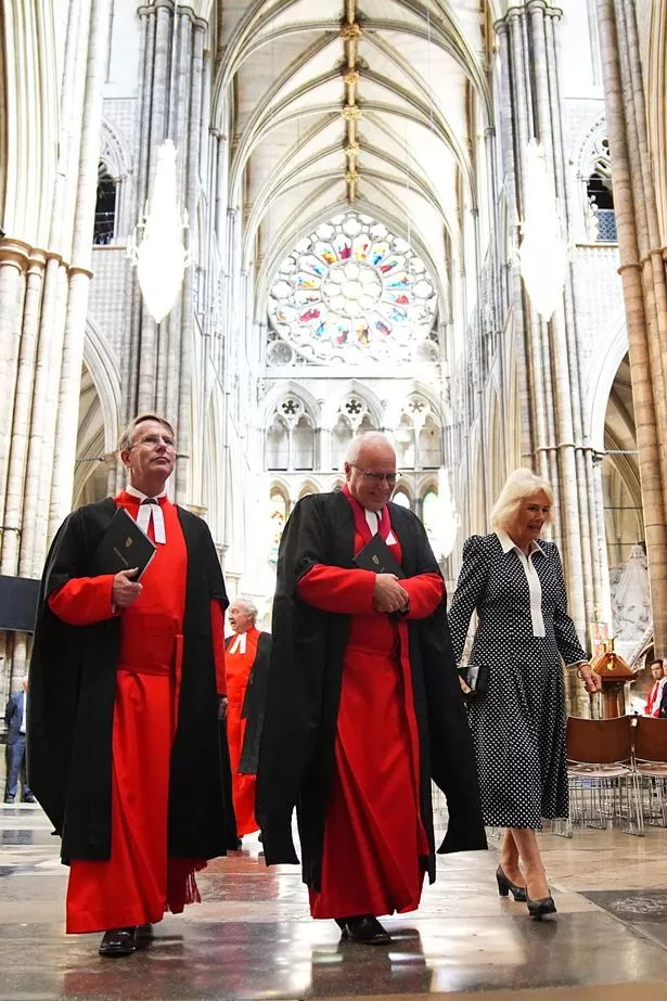 Queen Camilla with the Dean of Westminster, the Very Reverend Dr David Hoyle (centre) walking through Westminster Abbey
