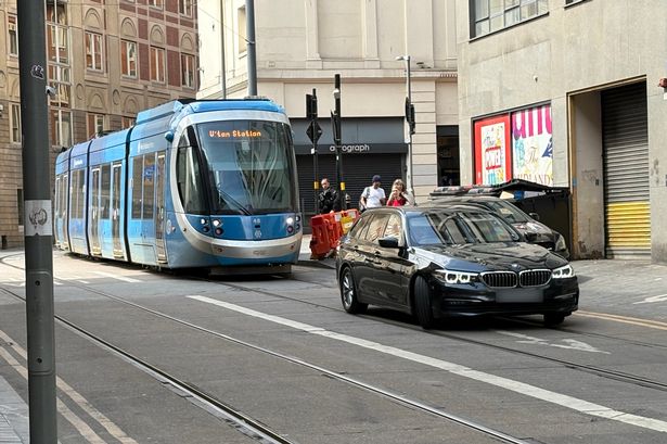 A BMW blocking the tram line outside New Street station