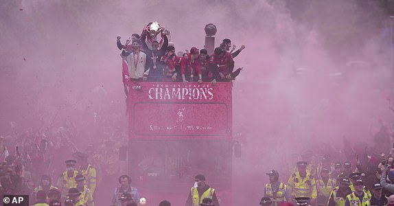 Liverpool players celebrate with the trophy on an open-top bus during the Liverpool FC Premier League victory parade in Liverpool, England, Monday, May 26, 2025.(AP Photo/Jon Super)