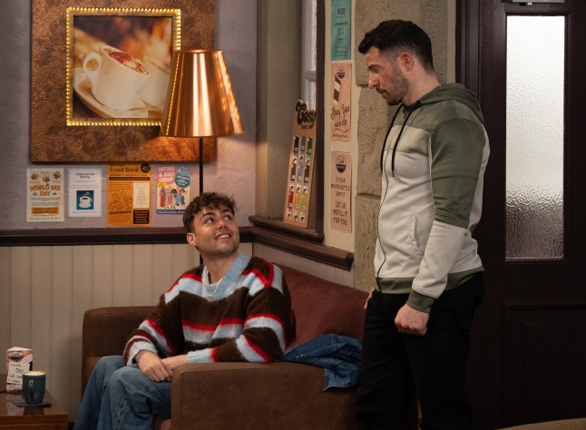 Lewis Barton looking up at brother Ross as they speak in the cafe in Emmerdale.