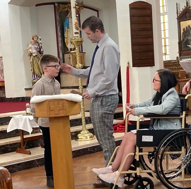 An image of a young boy, dark-haired man and dark-haired woman, who is in a wheelchair, inside a church.