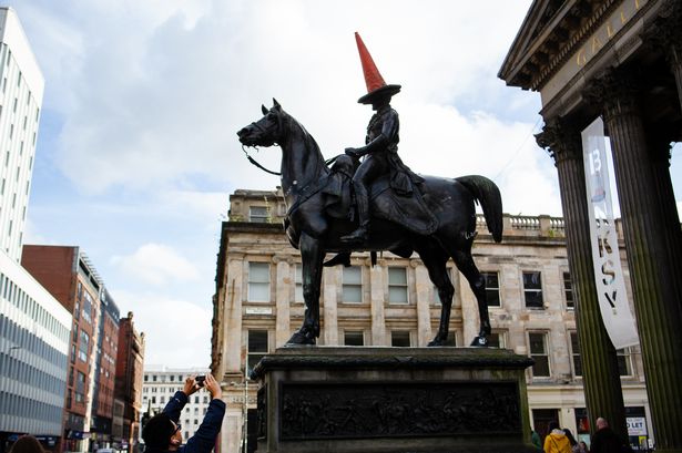 A picture of a tourist taking a photograph of the Duke of Wellington statue
