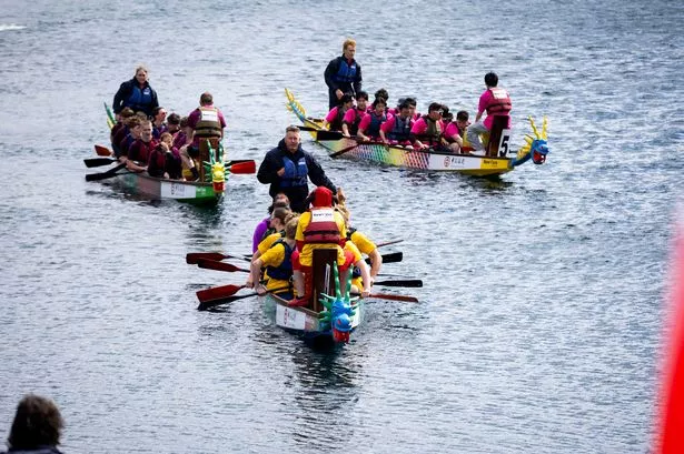 Boats with dragon head race down a part of Salford Quays to see who comes out on top