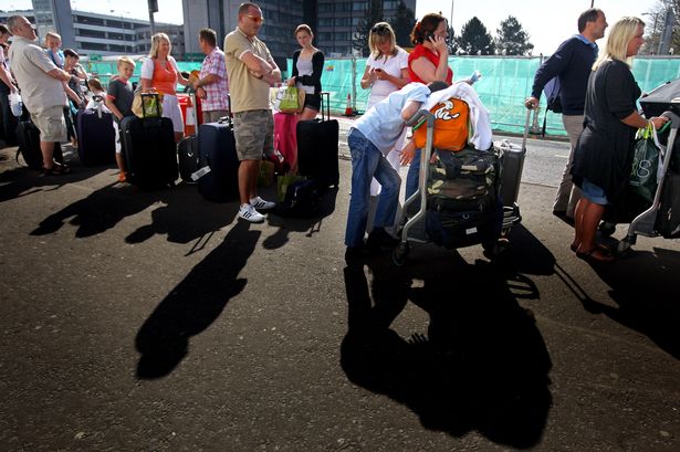 Passengers who arrived back to Glasgow on a flight from the Dominican Republic wait in a queue to get a transit bus