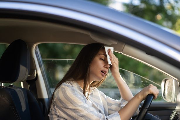 woman patting her head in car