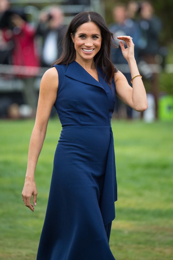 Meghan, Duchess of Sussex smiling in teal dress 