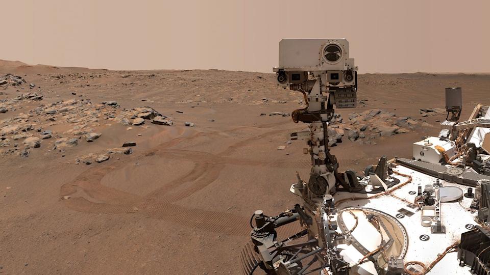A rocky, rust-colored landscape surrounds NASA's Perseverance Mars rover as it sits Martian soil.