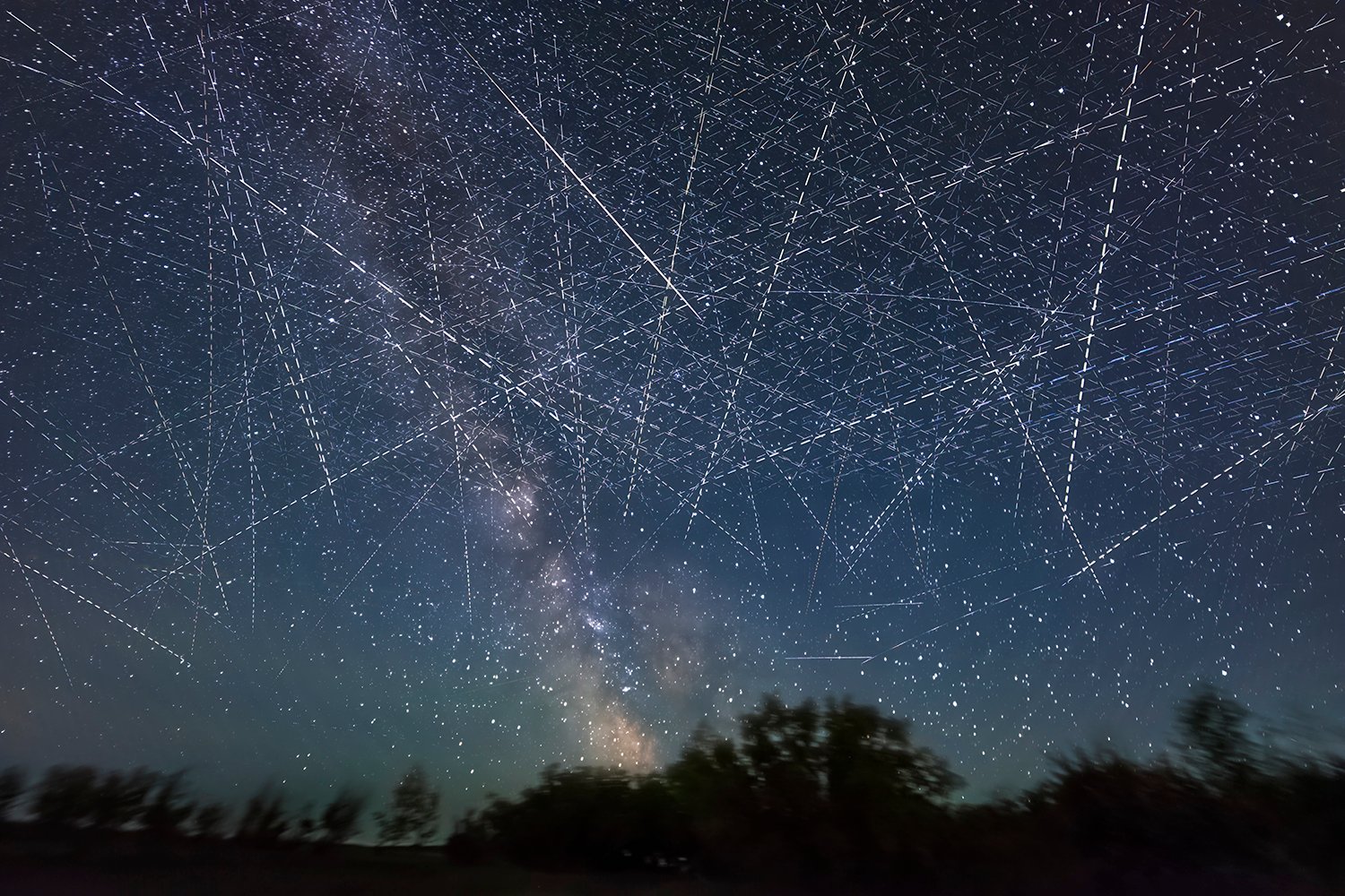 A photograph shows a timelapse image of satellites moving through the night sky.