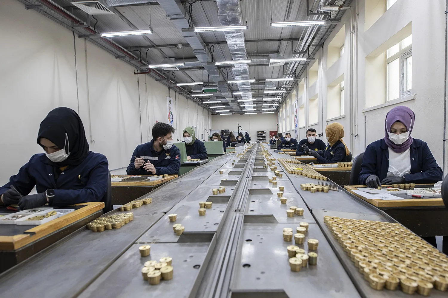 Two lines of employees are seen during their workday at a weapons manufacturer.