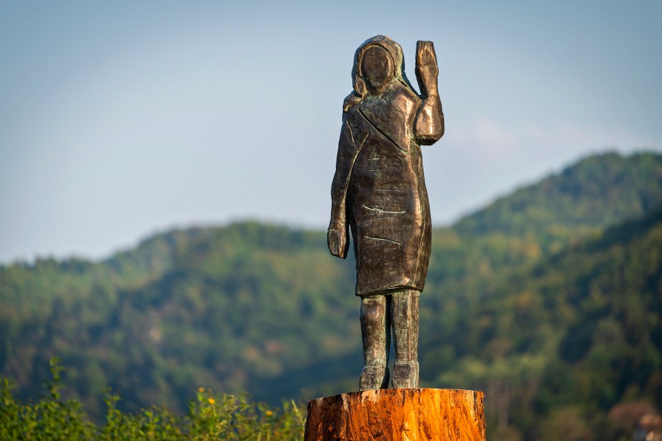 Bronze statue of Melania Trump on a tree stump.