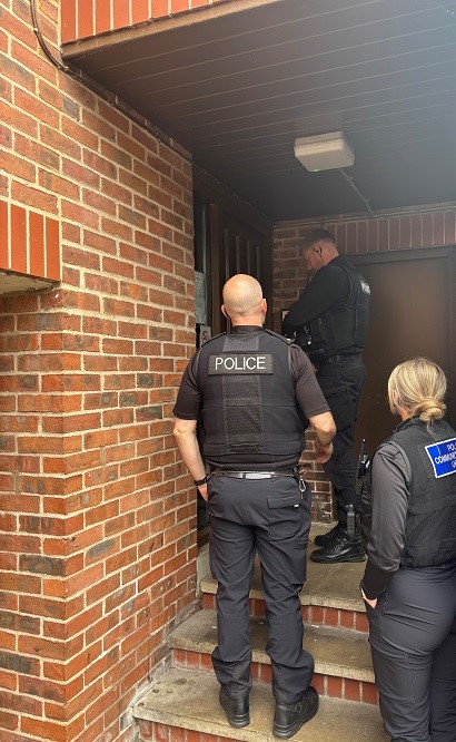 Police officers at a doorway during a raid.