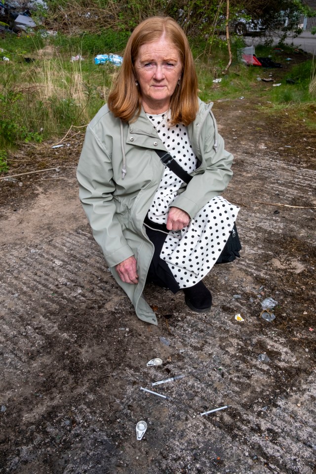 Woman sits near discarded drug paraphernalia.
