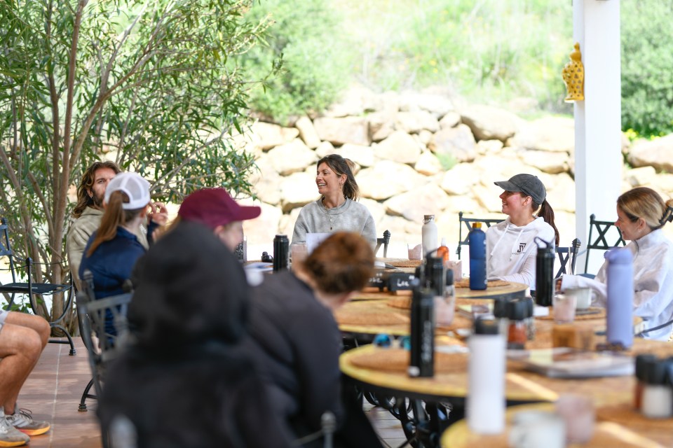 Group of people sitting around tables outdoors, talking.