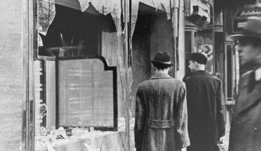 Germans pass by the smashed windows of a Jewish-owned shop after Kristallnacht