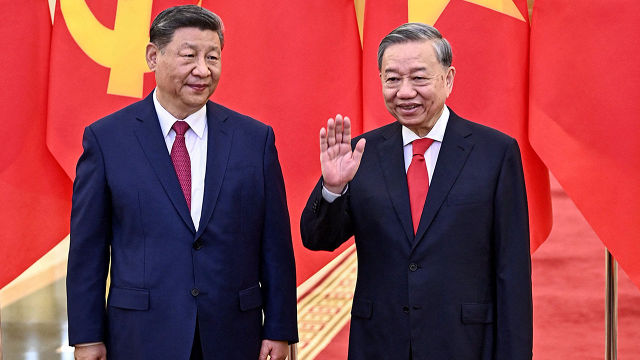 Vietnamese President To Lam waves while standing next to Chinese President Xi Jinping in Hanoi