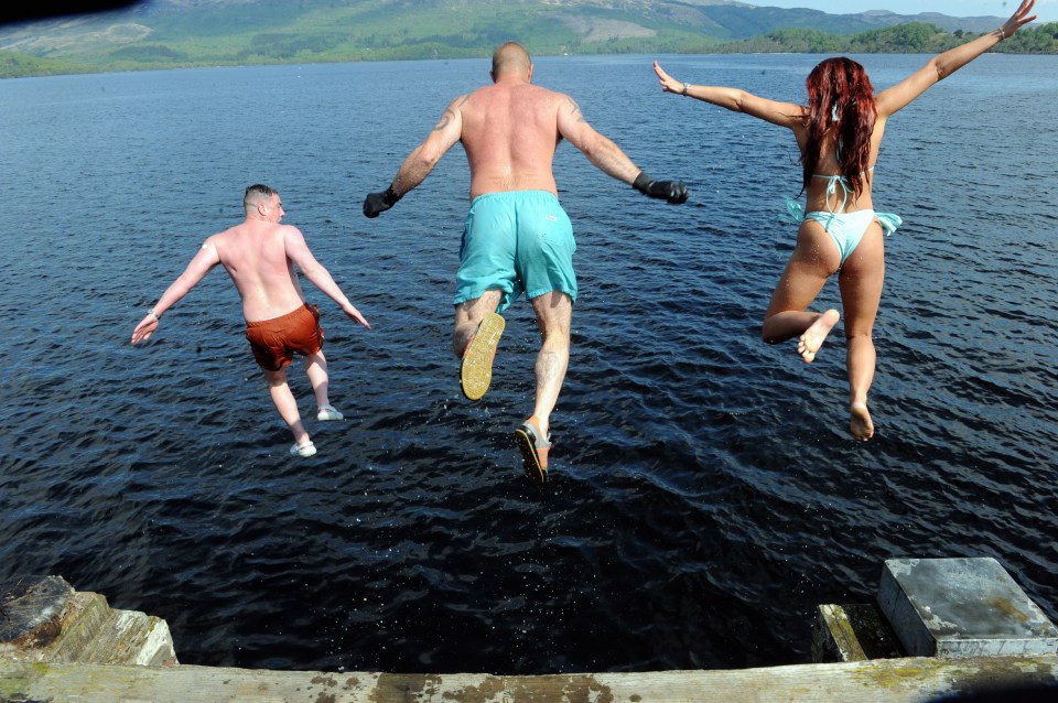 Two people jumping into the ocean from a stone pier.
