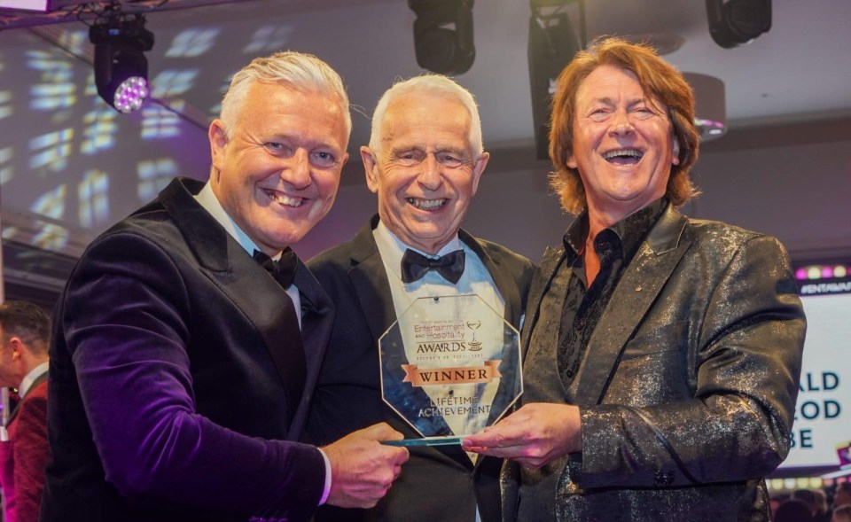 Three men holding a lifetime achievement award.