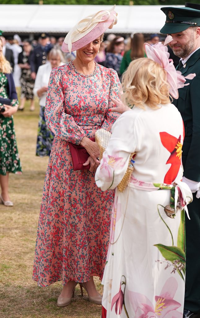 Sophie in pink floral dress talking to people in garden