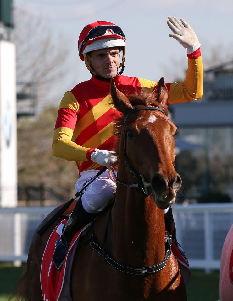 Jockey Noel Callow wins a horse race, raising his hand in victory.