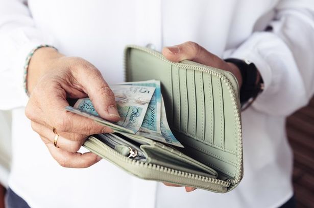 An unidentified elderly woman is taking money out of her purse 