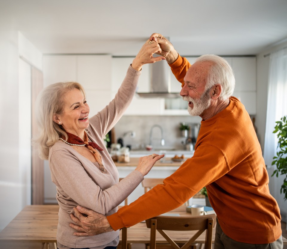 Happy senior couple dancing in their kitchen.