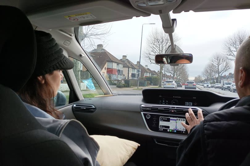 A photo of Anna and another person sitting in the front seat of a car